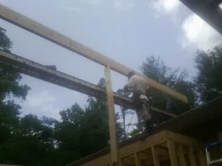 Carpenter setting a ridge beam over a new addition frame — Ice Dam Removal by Roofing Brothers in Grand View