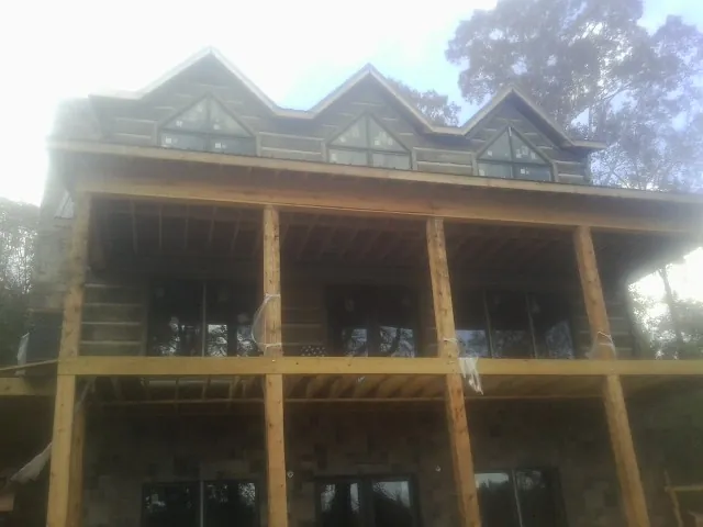 Dormers and porch framing on a large log home under construction — Roof Coating work by our crew in Grand View