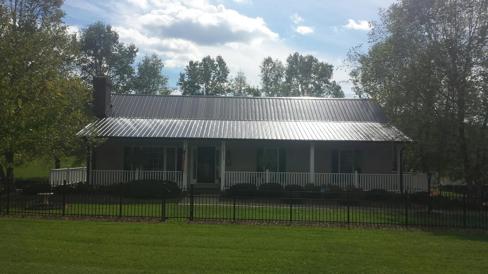 Gray metal roof on a brick ranch with a full width front porch — Gutter Guard Installation work by our crew in Grand View