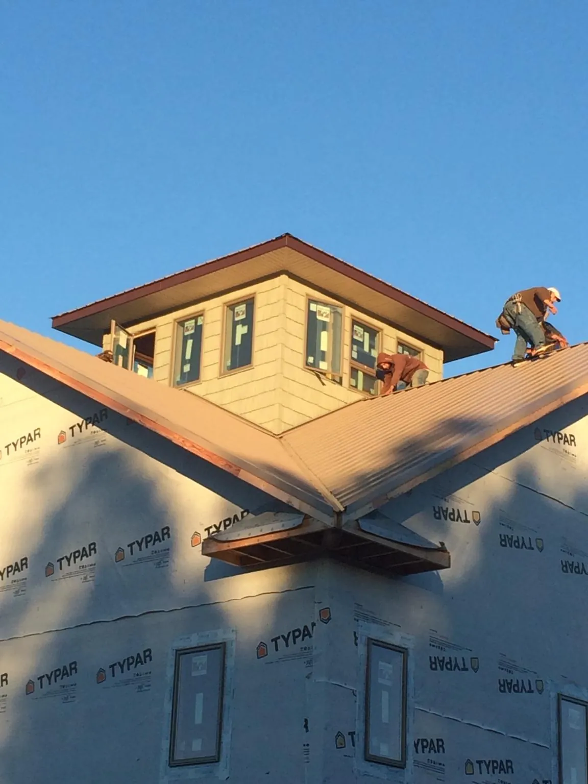 Roofers working around a rooftop cupola on a new metal roof at sunset — Roof Waterproofing in Grand View by Roofing Brothers